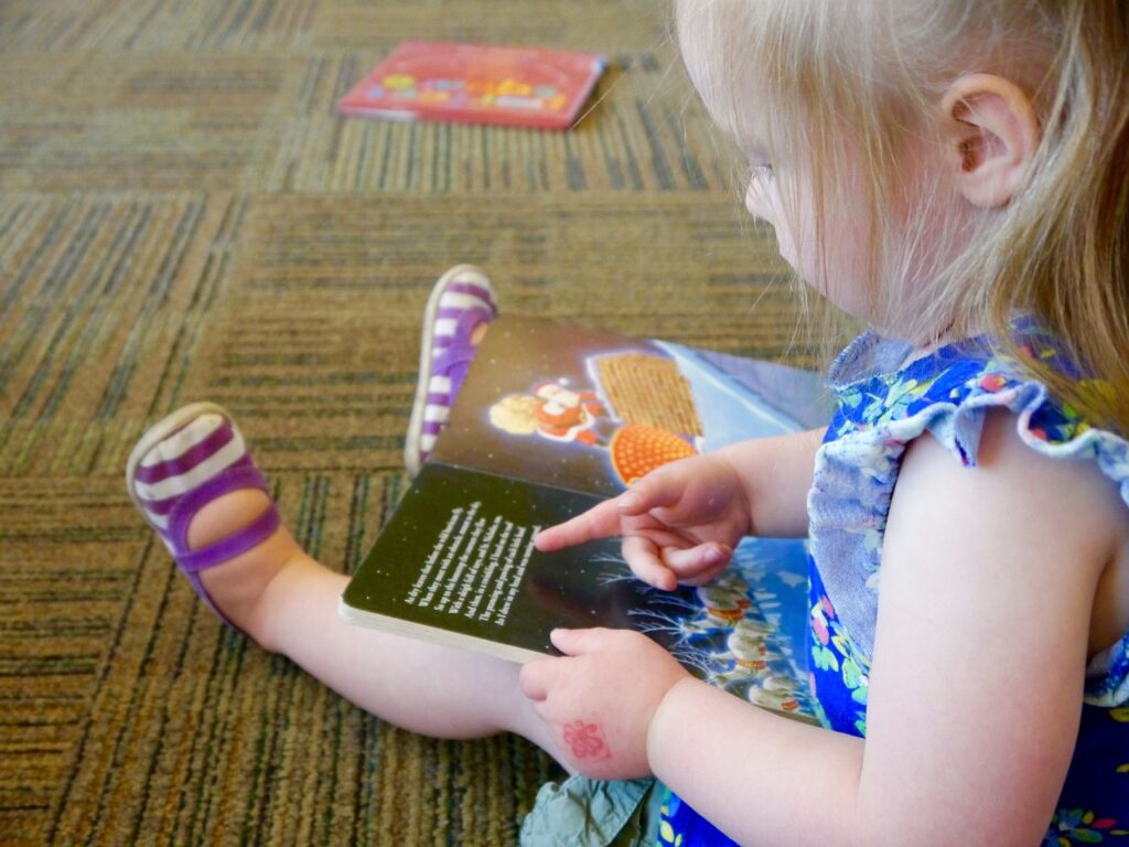 A little girl is looking at a book