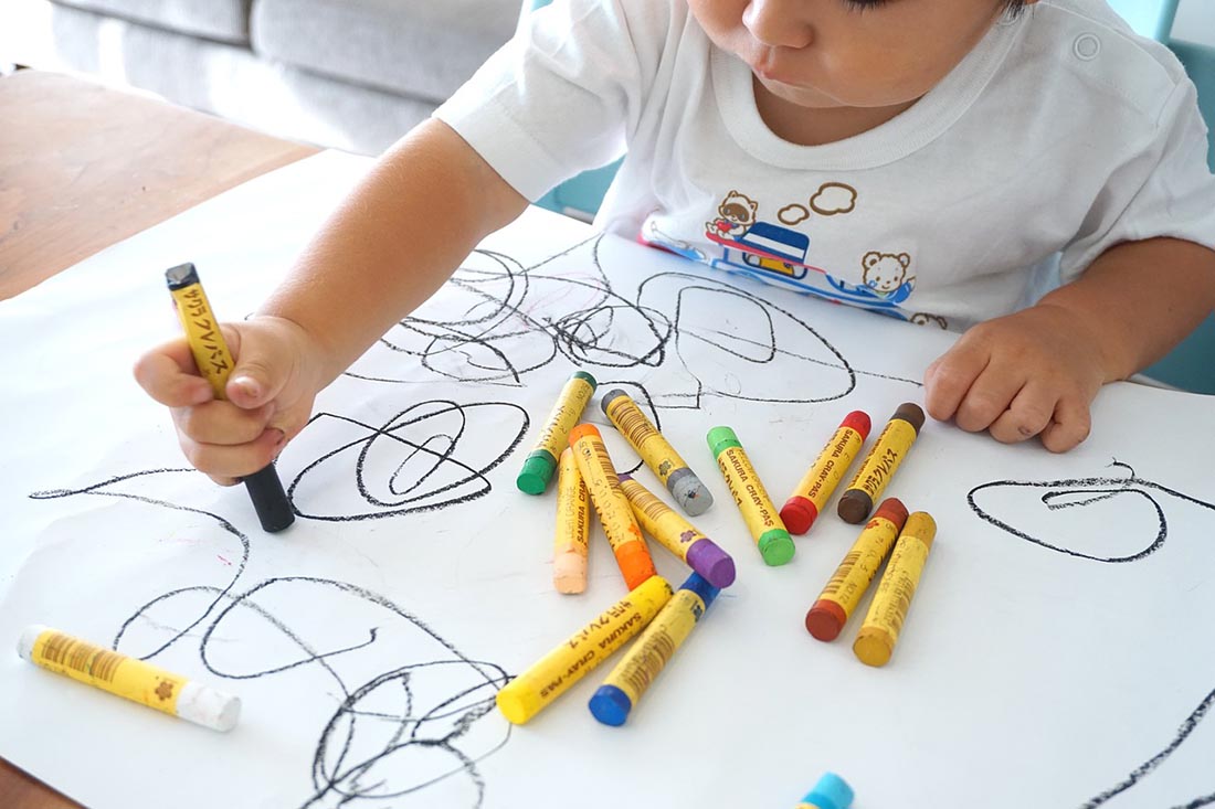 The child draws with wax colors, photo credit Oekaki Oe