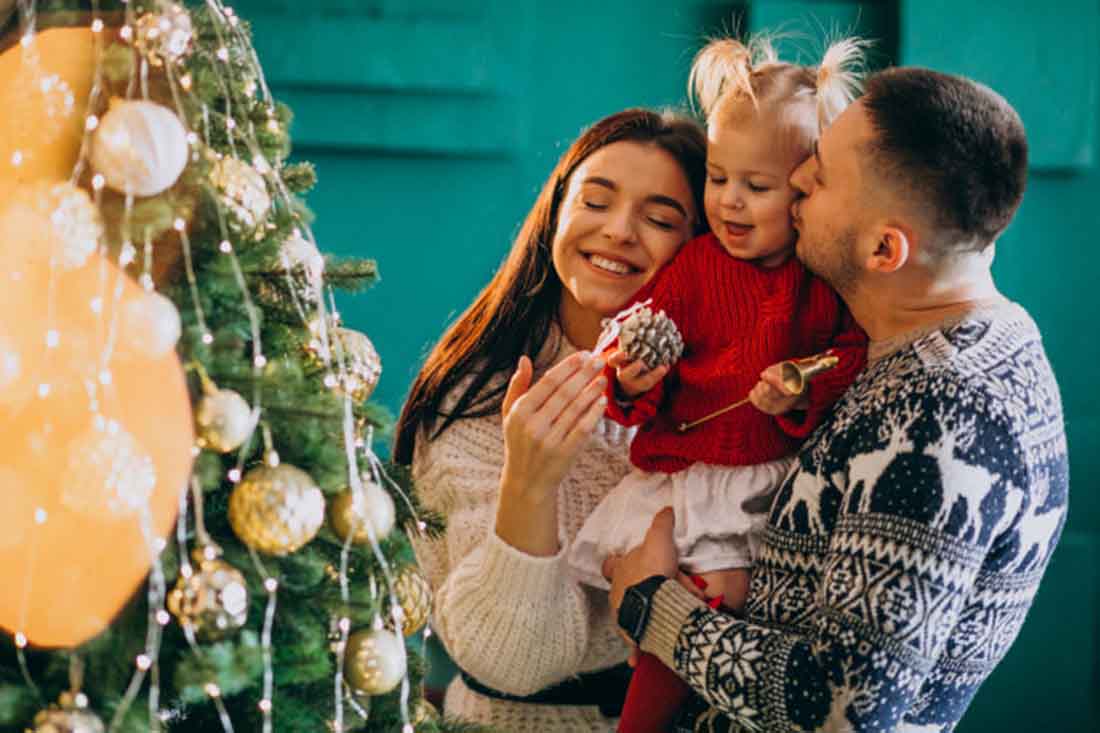 Family-with-little-daughter-hanging-toys-christmas-tree, photo credit Sanivpetro