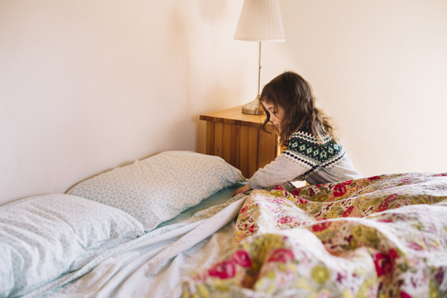 The girl sets the bedding on the bed , Freepik