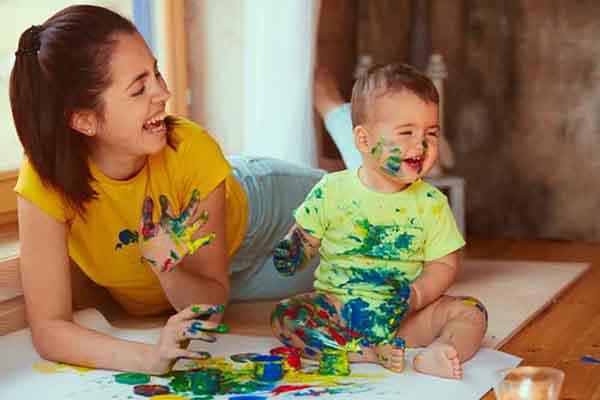 Mother with son painting big paper with their hands, photo credit Freepik