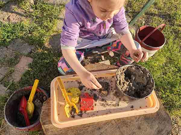 The girl is playing in the mud and sand